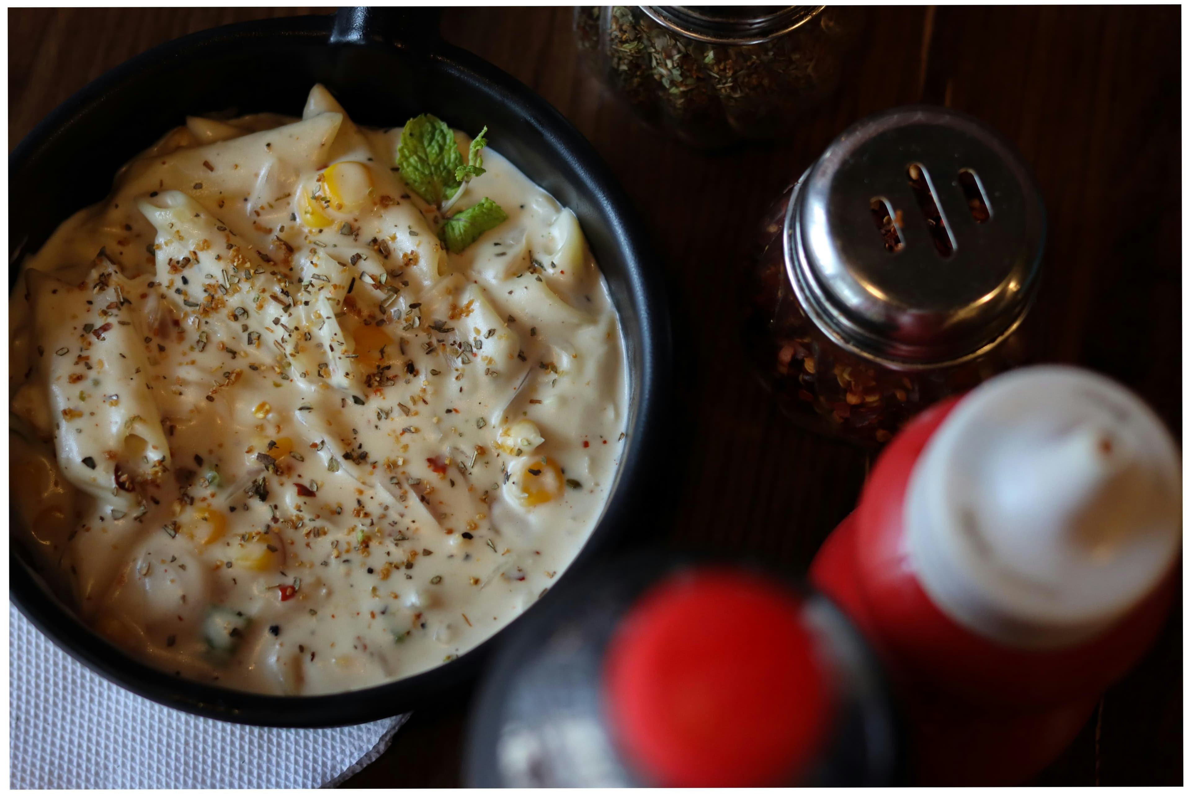 Creamy corn pasta in a white bowl with fresh herbs
